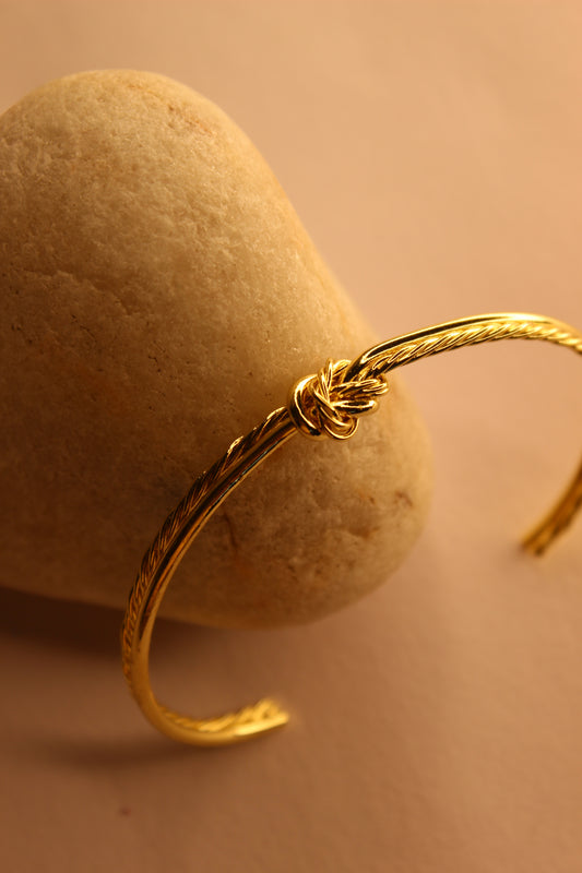 Knota Cuff Bracelet on a textured beige surface
