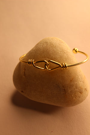 Tether Cuff Bracelet on a heart-shaped stone with a soft yellow background