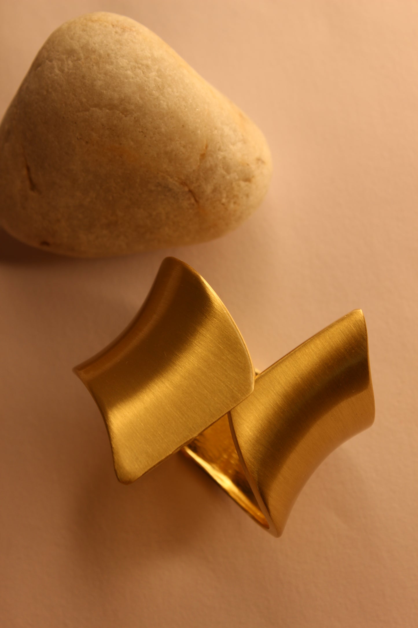 Arcus Bracelet next to a stone on a beige background