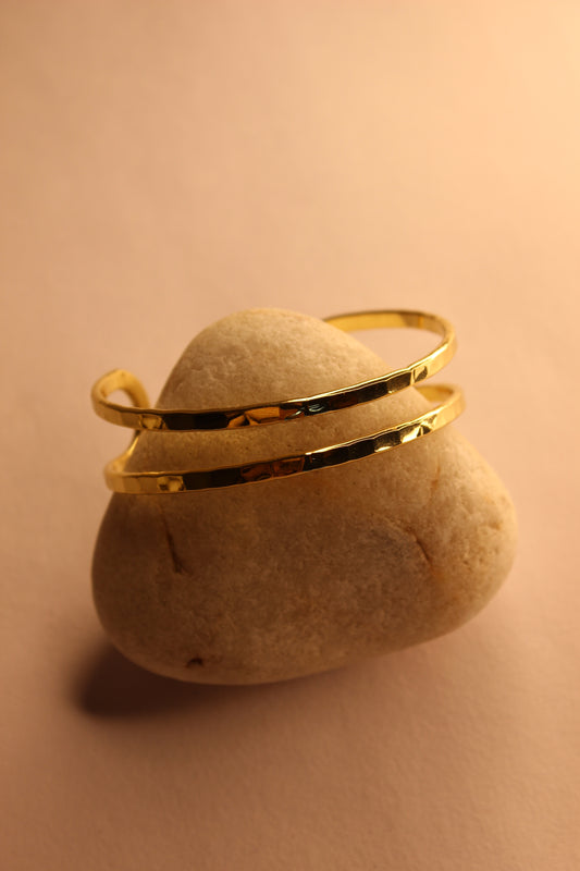 Elaris Cuff Bracelet on a beige stone with a soft pink background