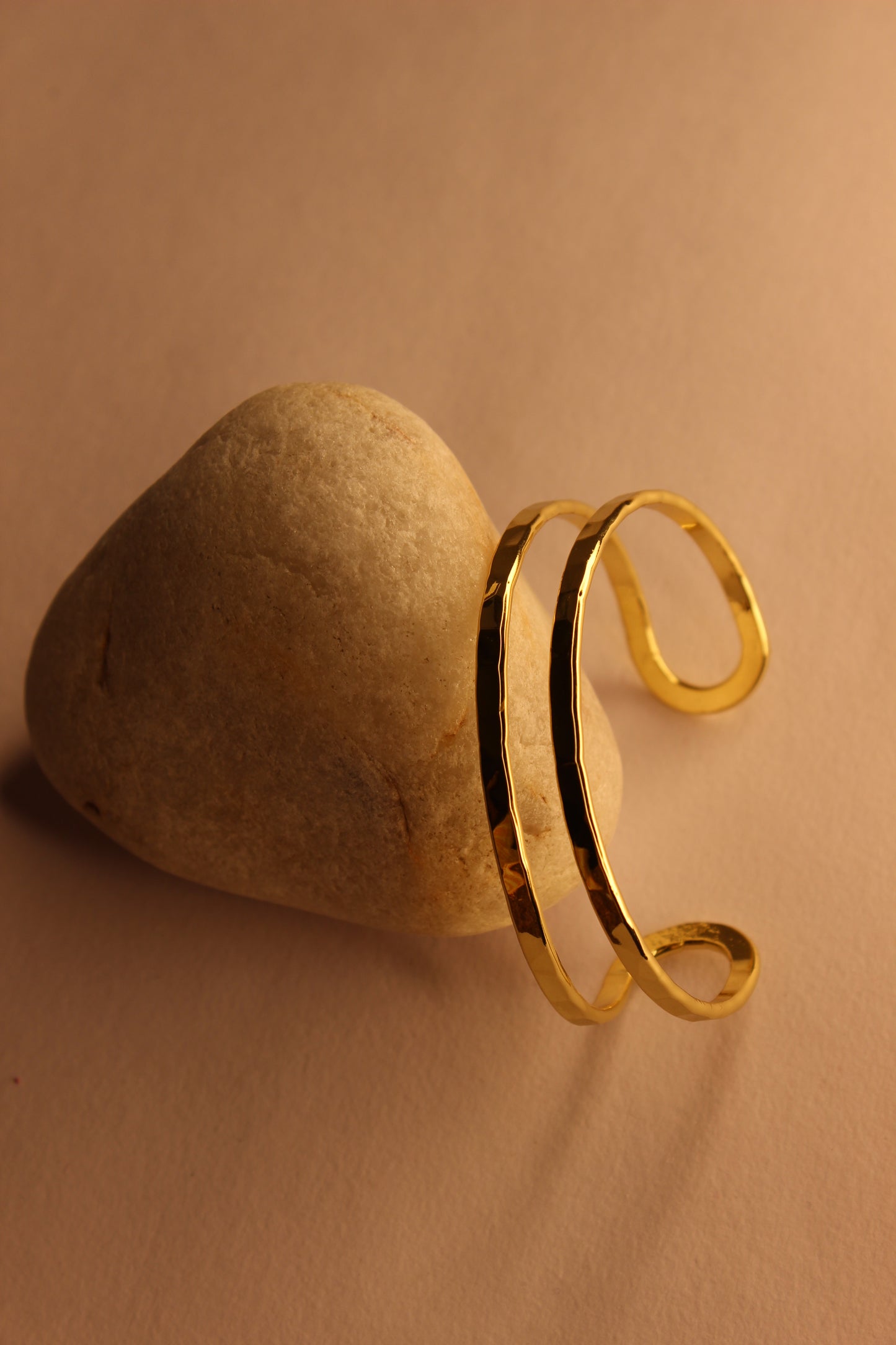 Elaris Cuff Bracelet on a stone with a beige background
