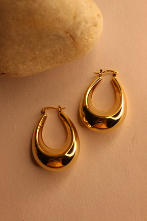 Pair of Solara Hoop Earrings on a beige surface