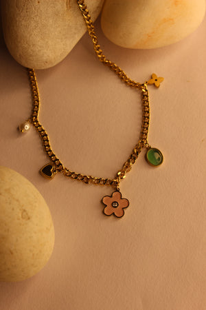 WishBlush Charms Necklace displayed on stones with yellow background, highlighting elegant charms design