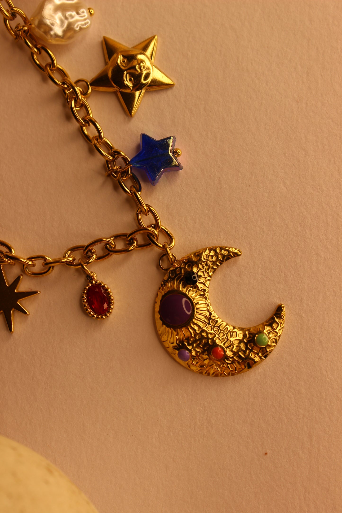 Lunar Spells Charms Necklace with star, moon, and starfish charms on a beige background