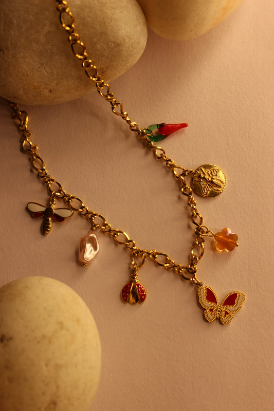 Wild Keepsake Charms Necklace with gold chain and colorful charms on white lace fabric