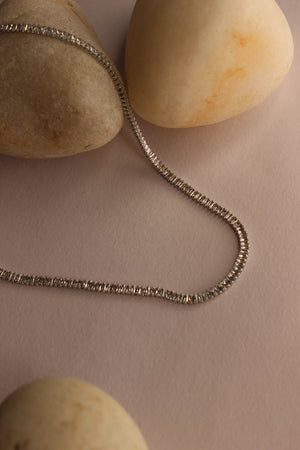 Twilite Necklace on a beige surface with stones
