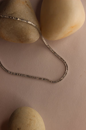 Twilite Necklace on a beige surface with stones