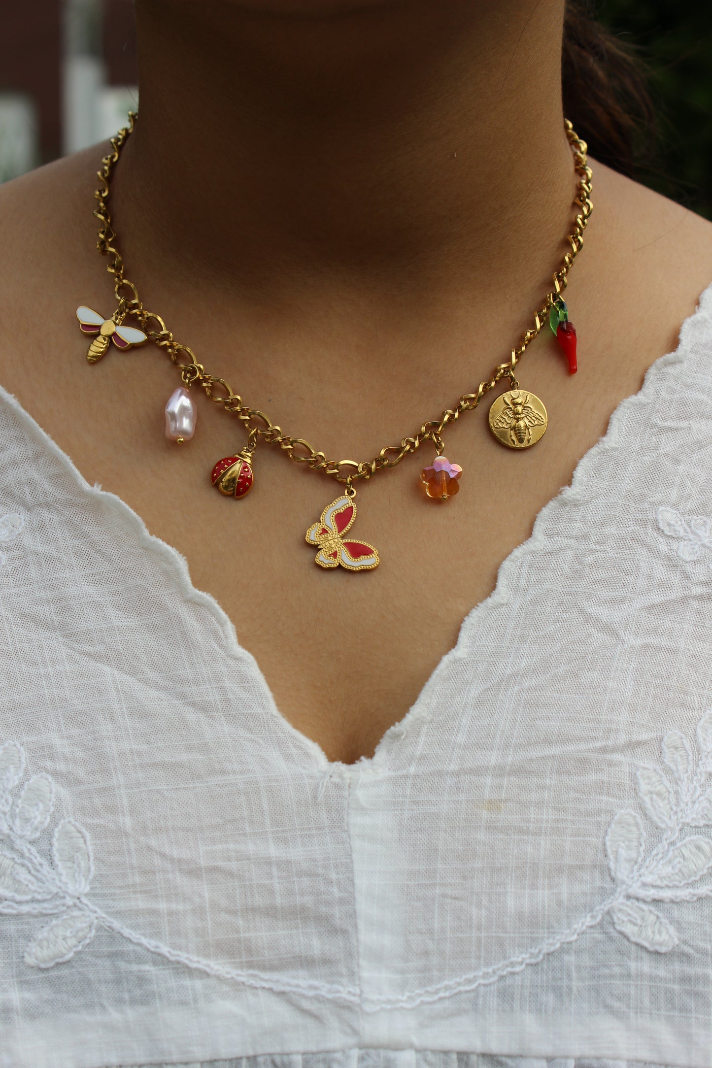 Close-up of model’s neck showcasing gold charm necklace with nature-inspired pendants