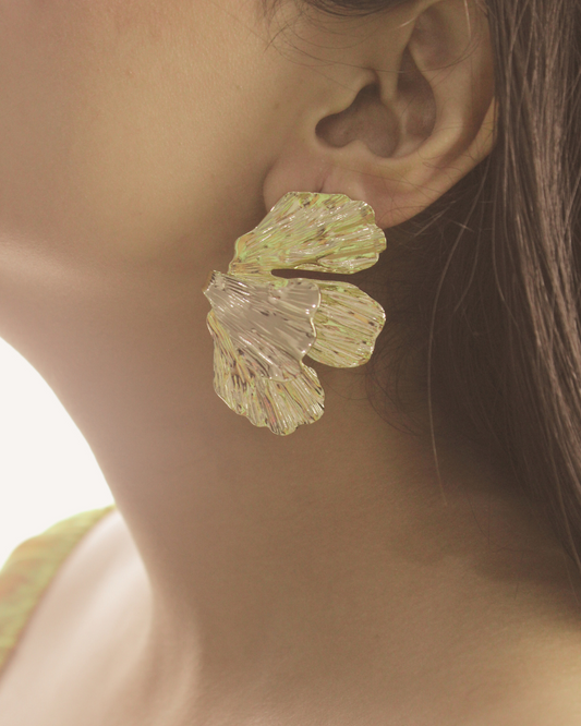 Close-up of a model wearing large, Ethereal Fleur Earrings with a blurred background