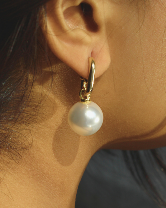 Luna Pearla Earrings on an ear with a neutral background