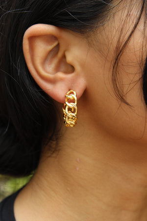 Close-up of an ear wearing a Tied in Gold Hoop Earrings with blurred background