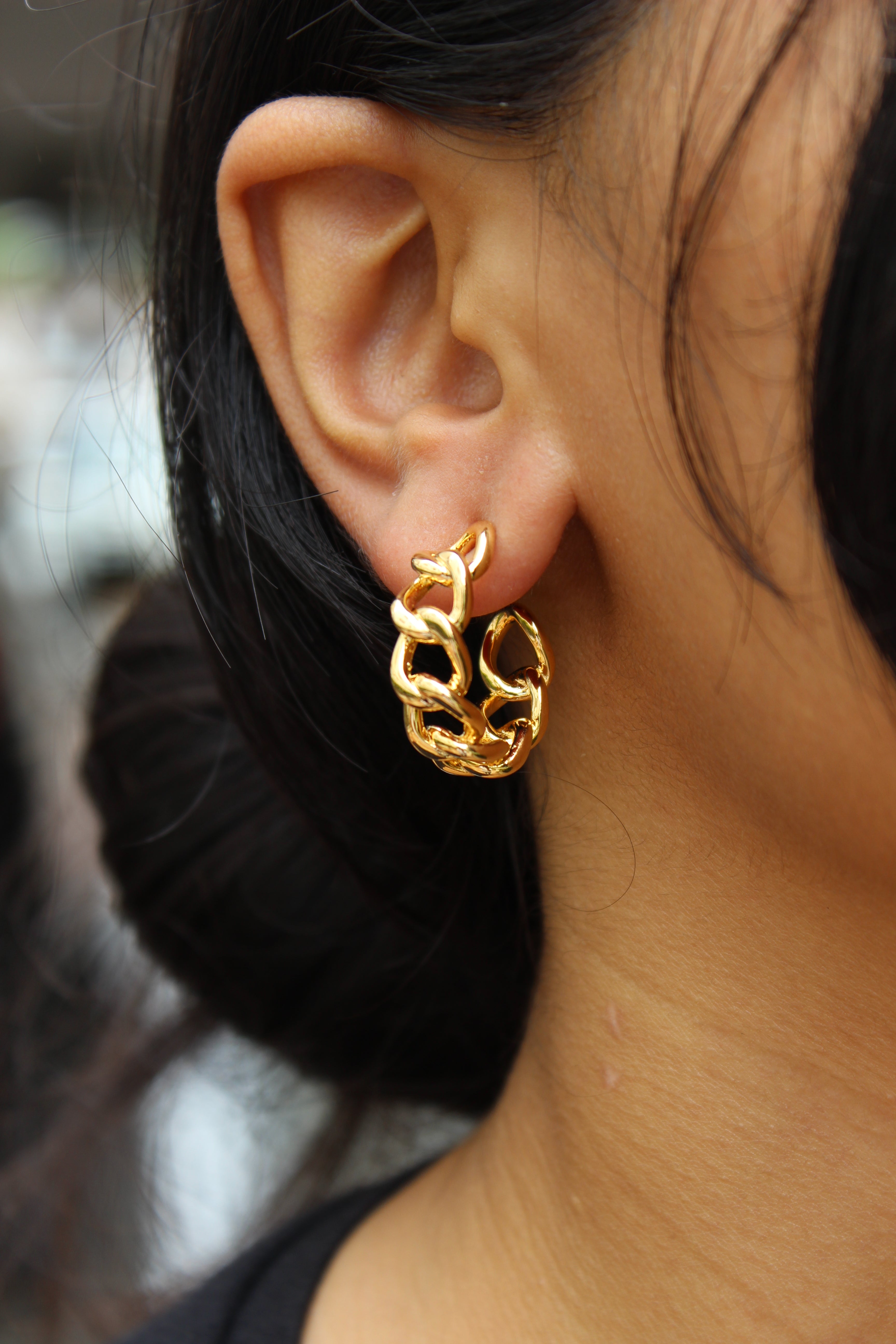 Close-up of a model wearing a Tied in Gold Hoop Earrings with a blurred background