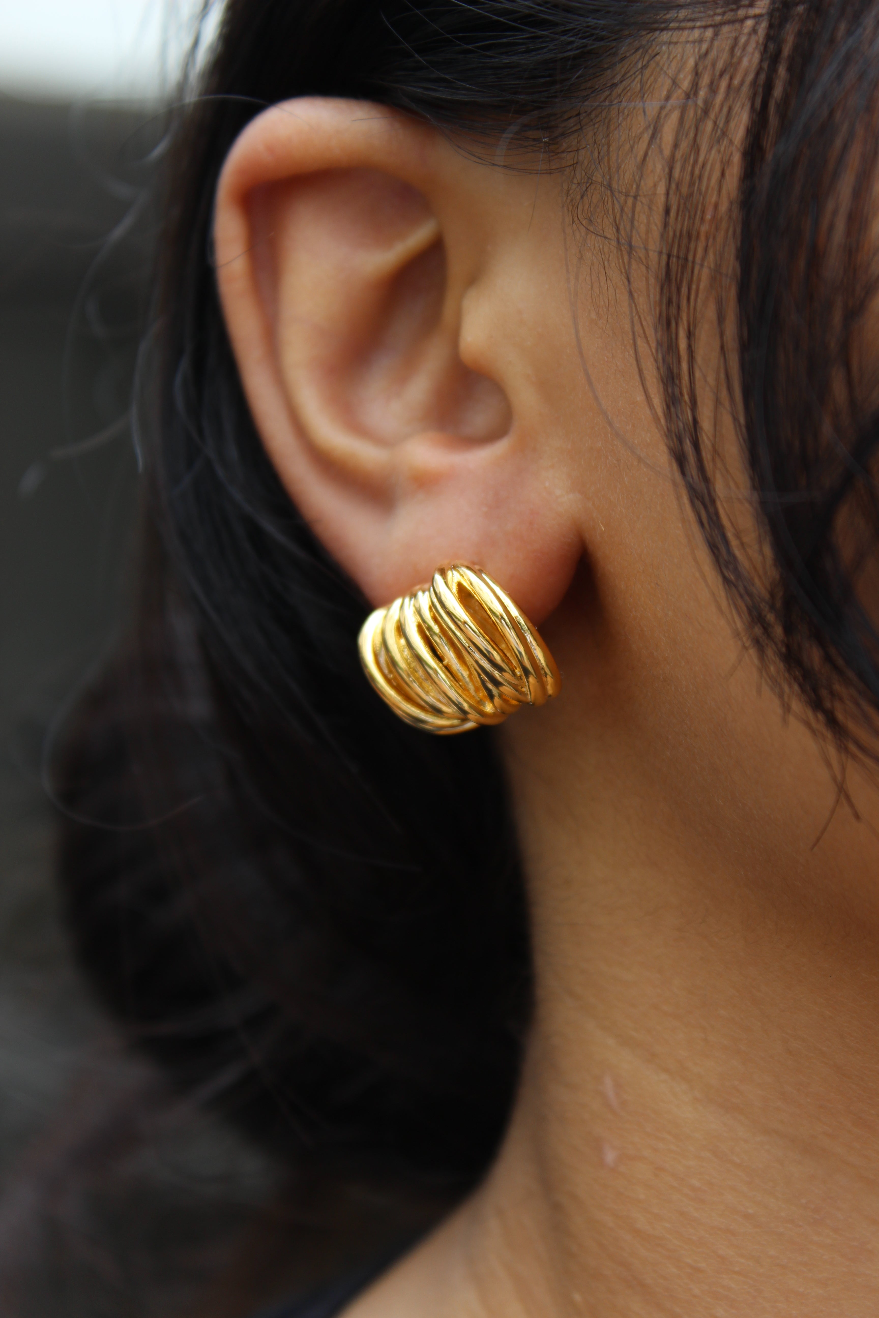 Close-up of a model wearing a Elektra Stud Earrings with a blurred background