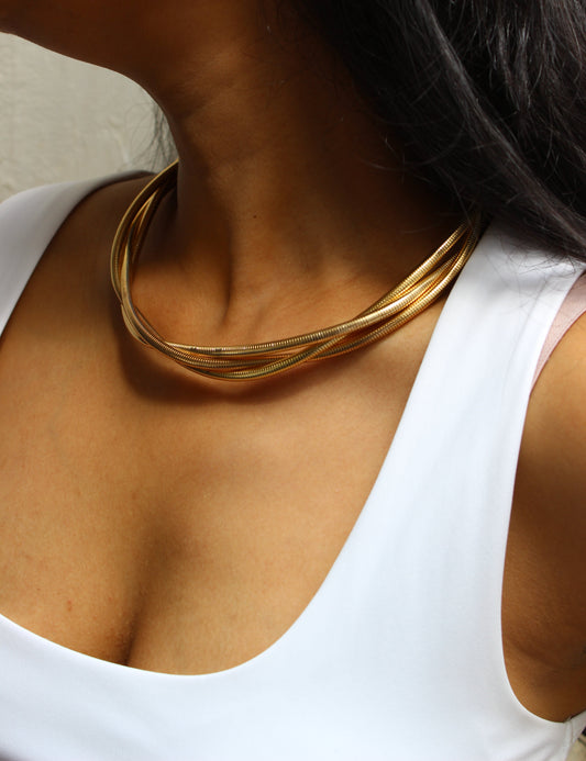 Close-up of a model wearing a white top with a Torra Necklace on a neutral background