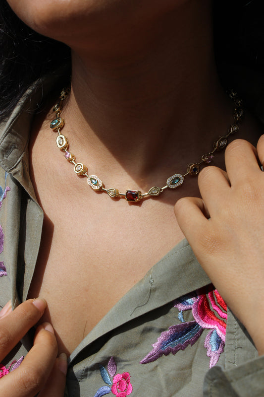 Close-up of a model wearing a decorative anklet with Solstice Waltz Necklace on a dark background.
