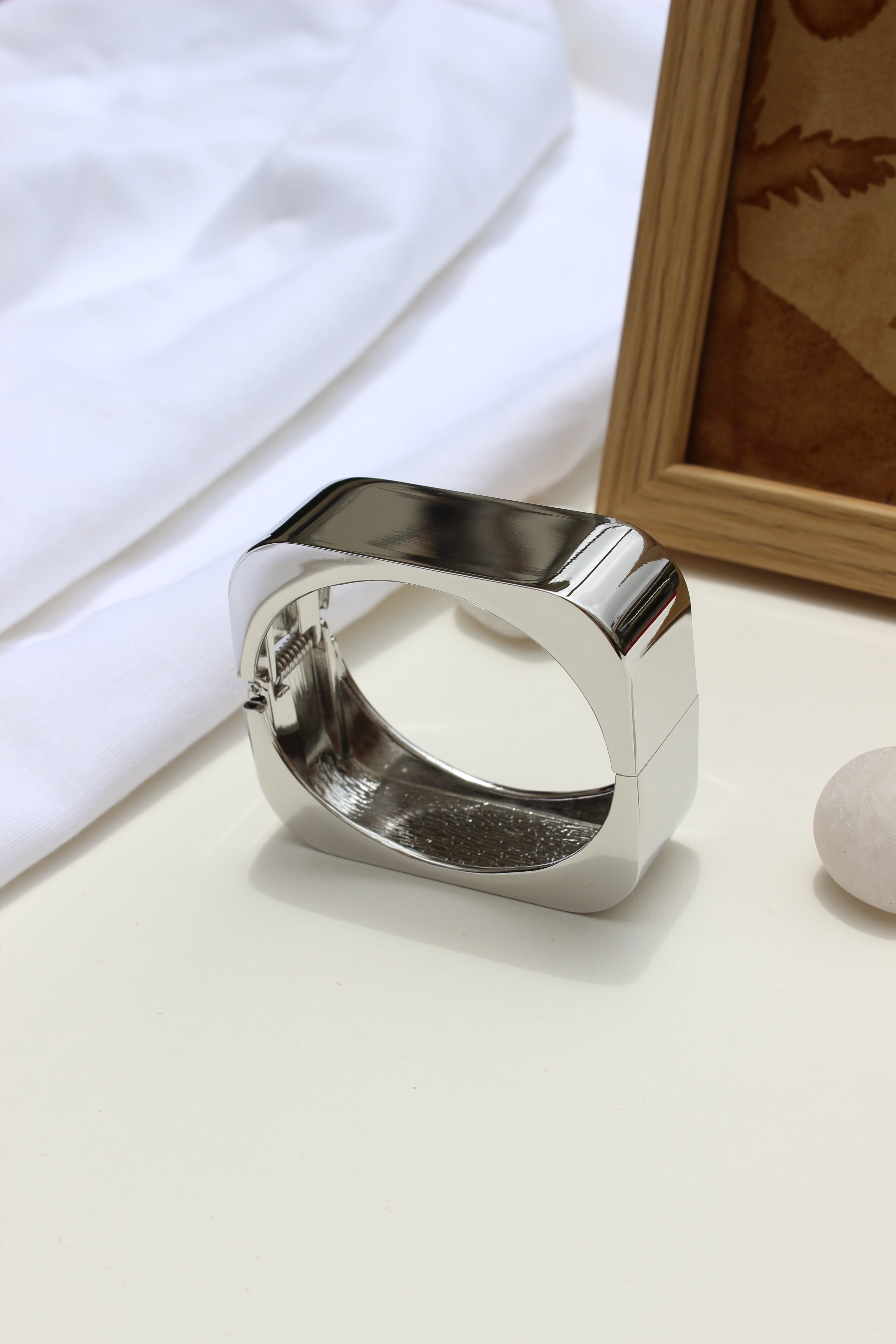 Lucid Hour Bracelet on a white surface with a wooden frame in the background