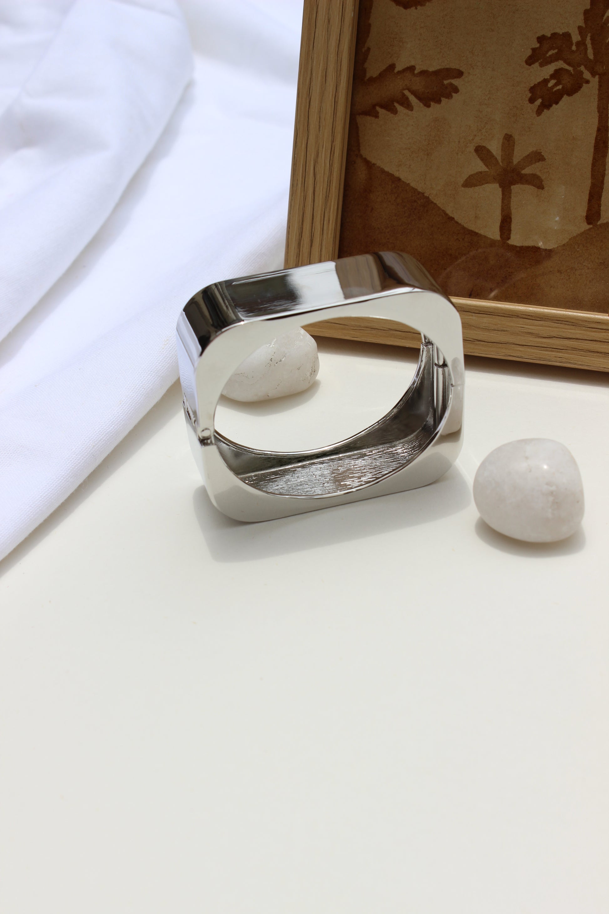 Lucid Hour Bracelet on a white surface with a framed picture in the background