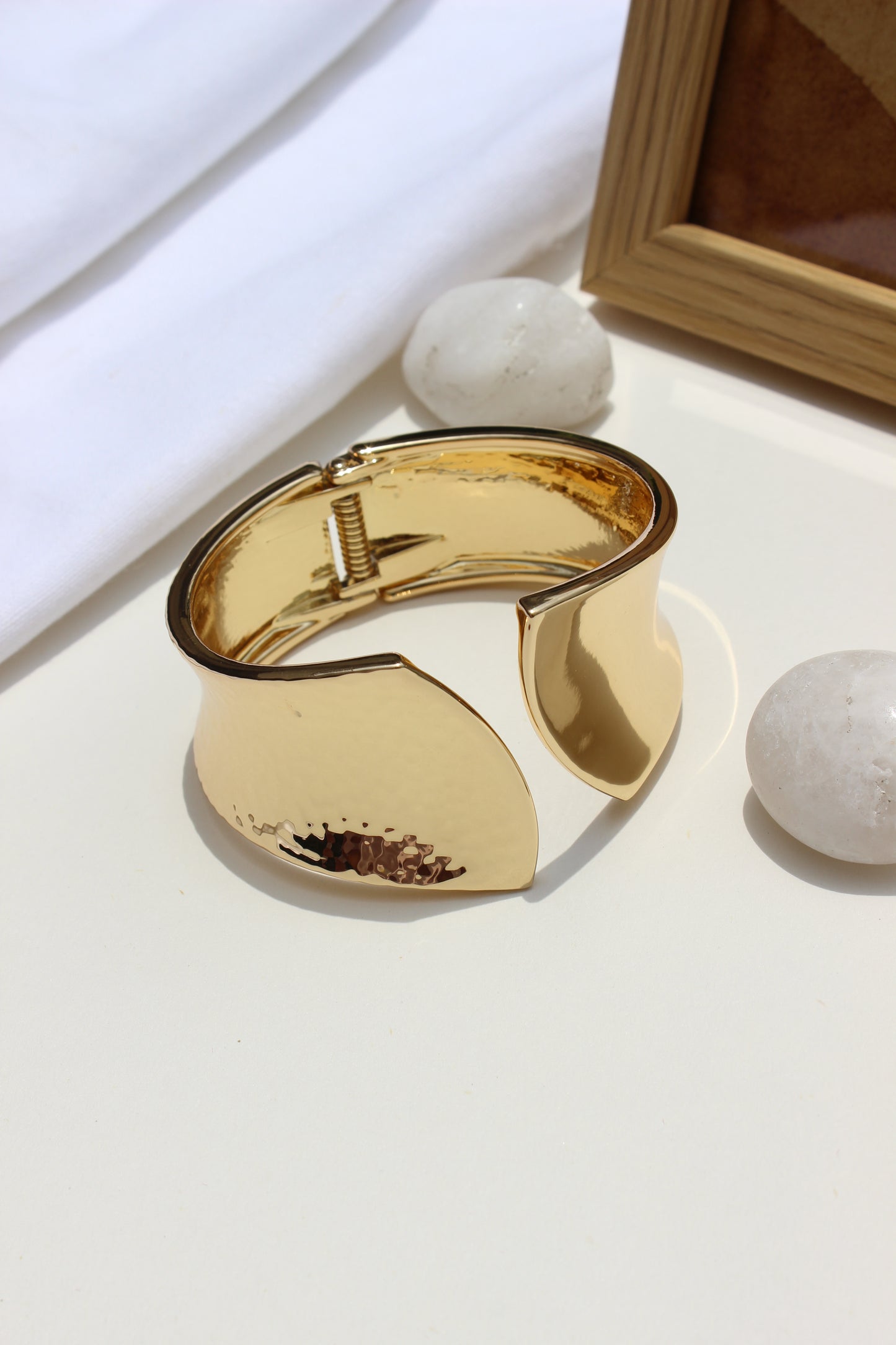 Sculpted Quiet Bracelet on a light surface with a wooden frame in the background
