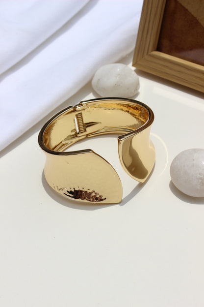 Sculpted Quiet Bracelet on a light surface with a wooden frame in the background