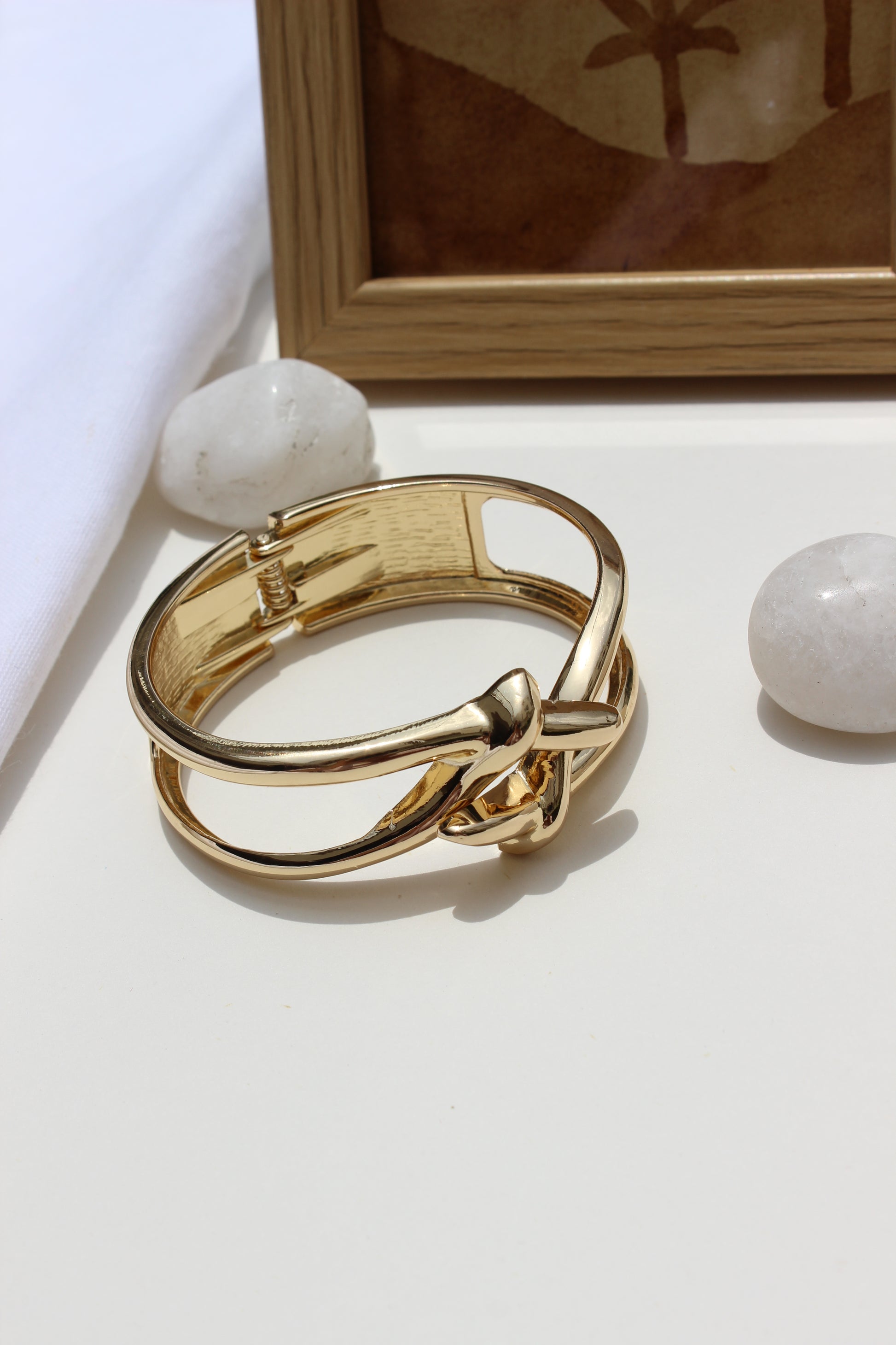 Orbit Wrap Bracelet on a white surface with a wooden frame and marble stone in the background