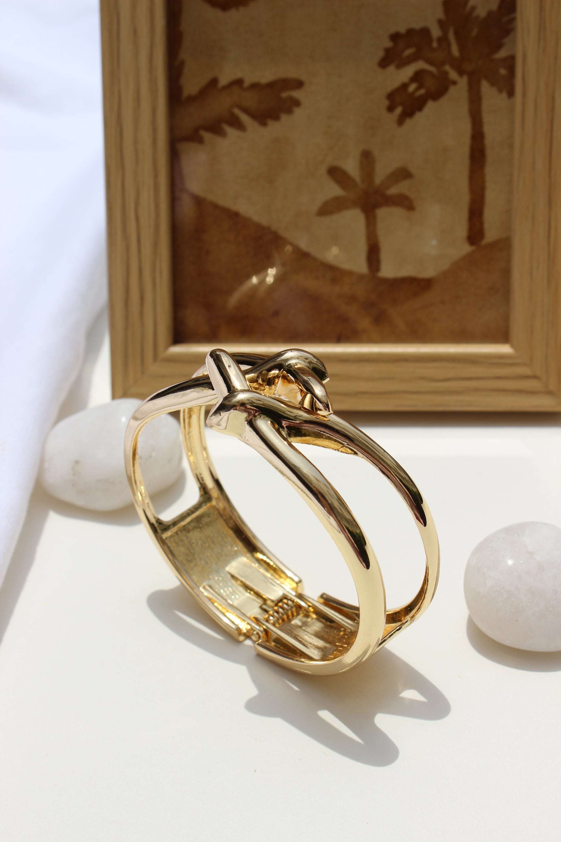 Orbit Wrap Bracelet on a white surface with a wooden frame in the background