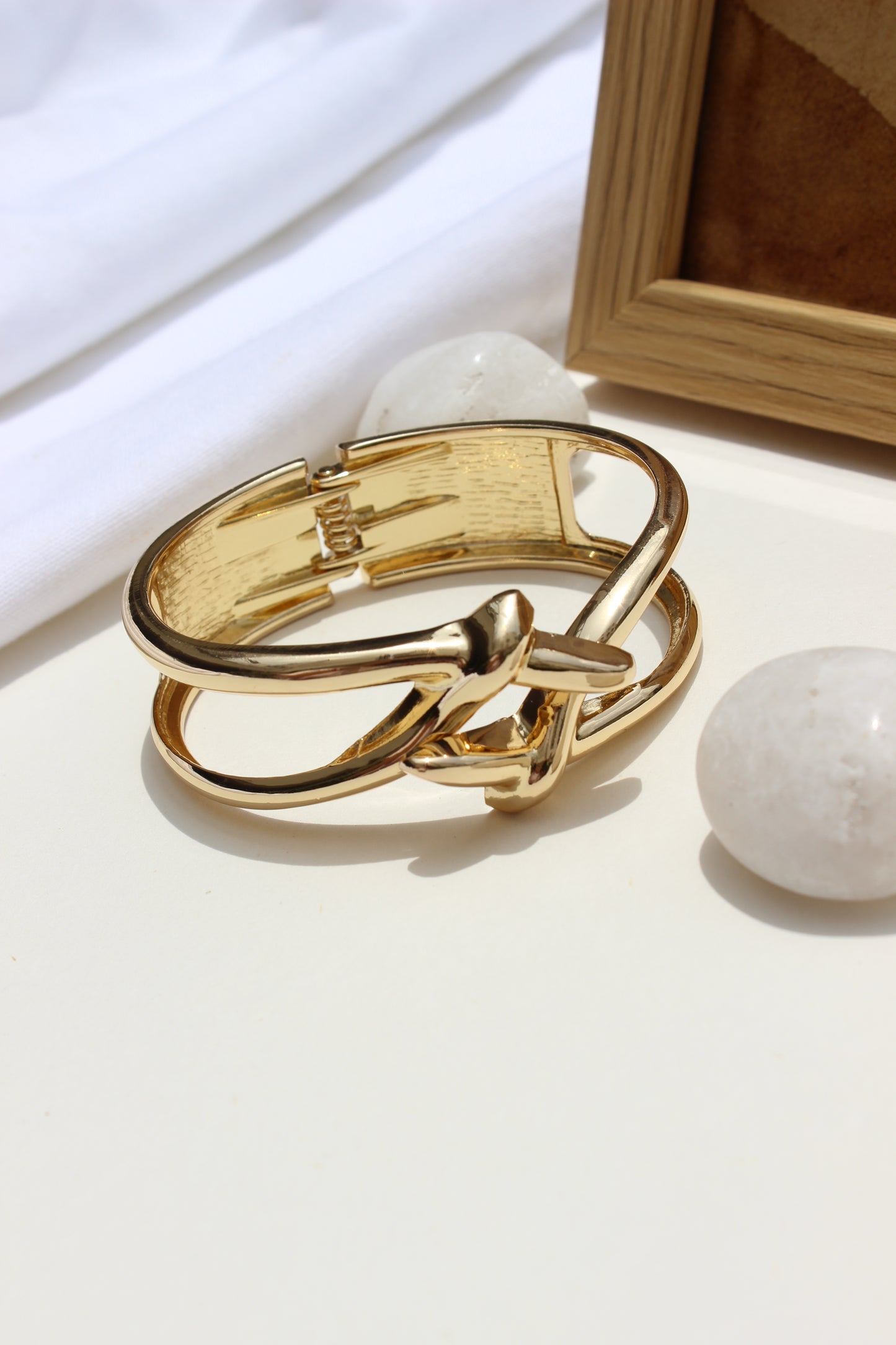Orbit Wrap Bracelet on a white surface with a wooden frame and stones in the background