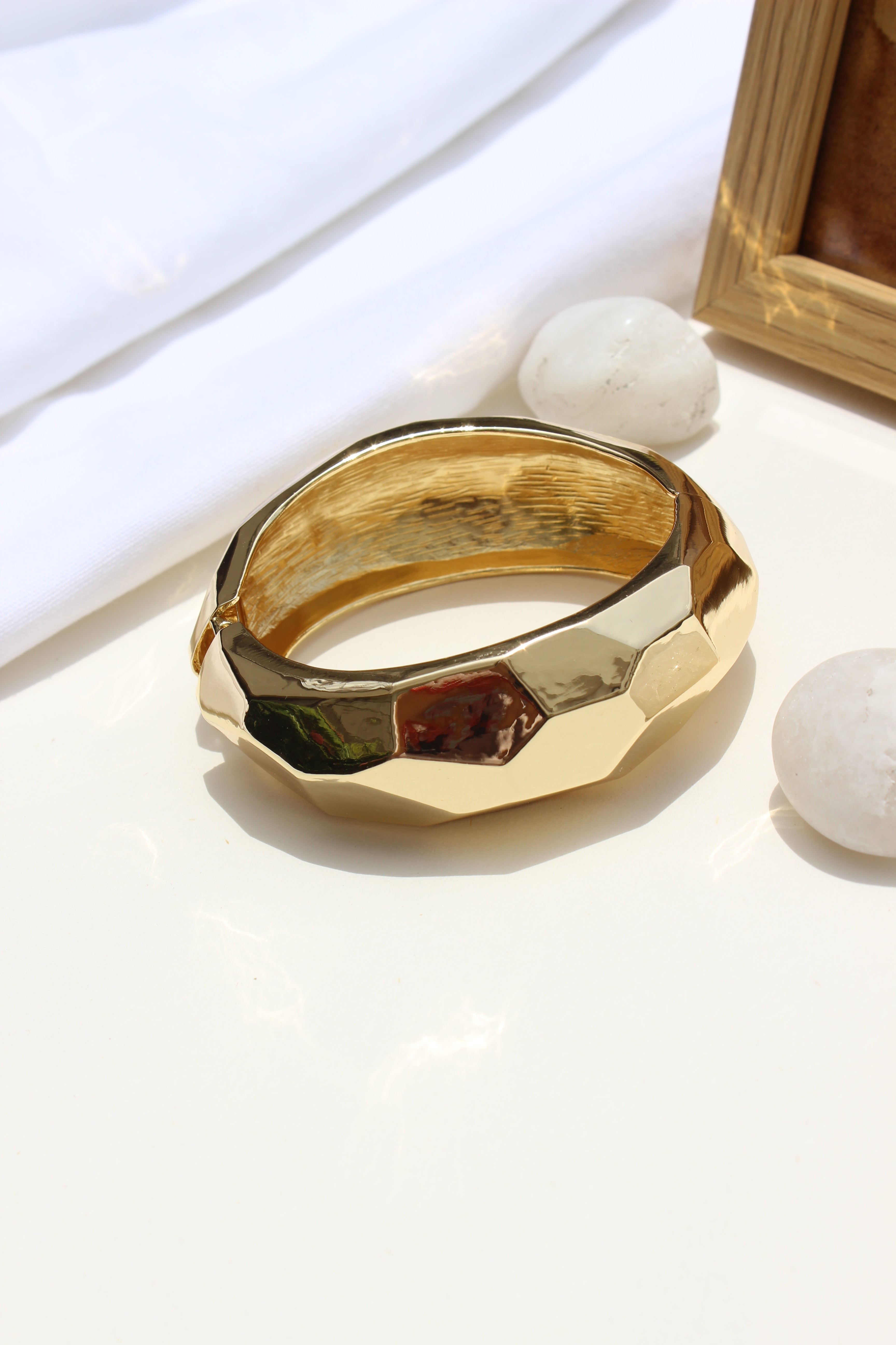 Golden Pause Bracelet on a white surface with a blurred background