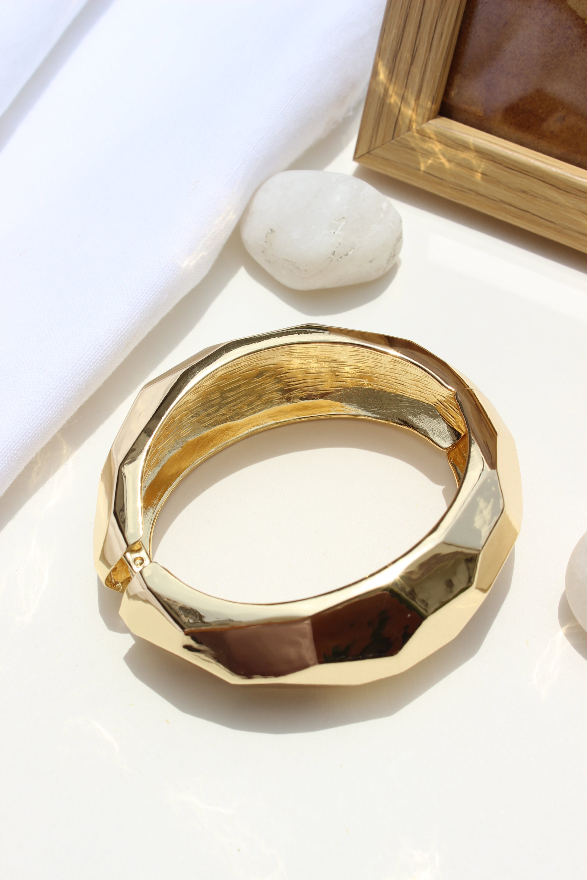 Golden Pause Bracelet on a white surface with a blurred background