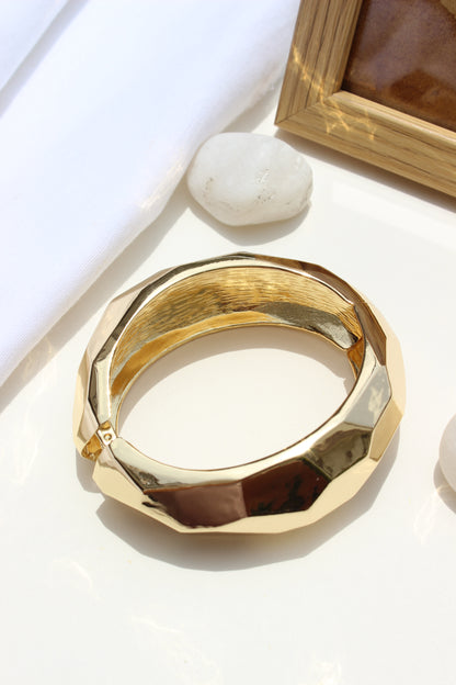 Golden Pause Bracelet on a white surface with a blurred background