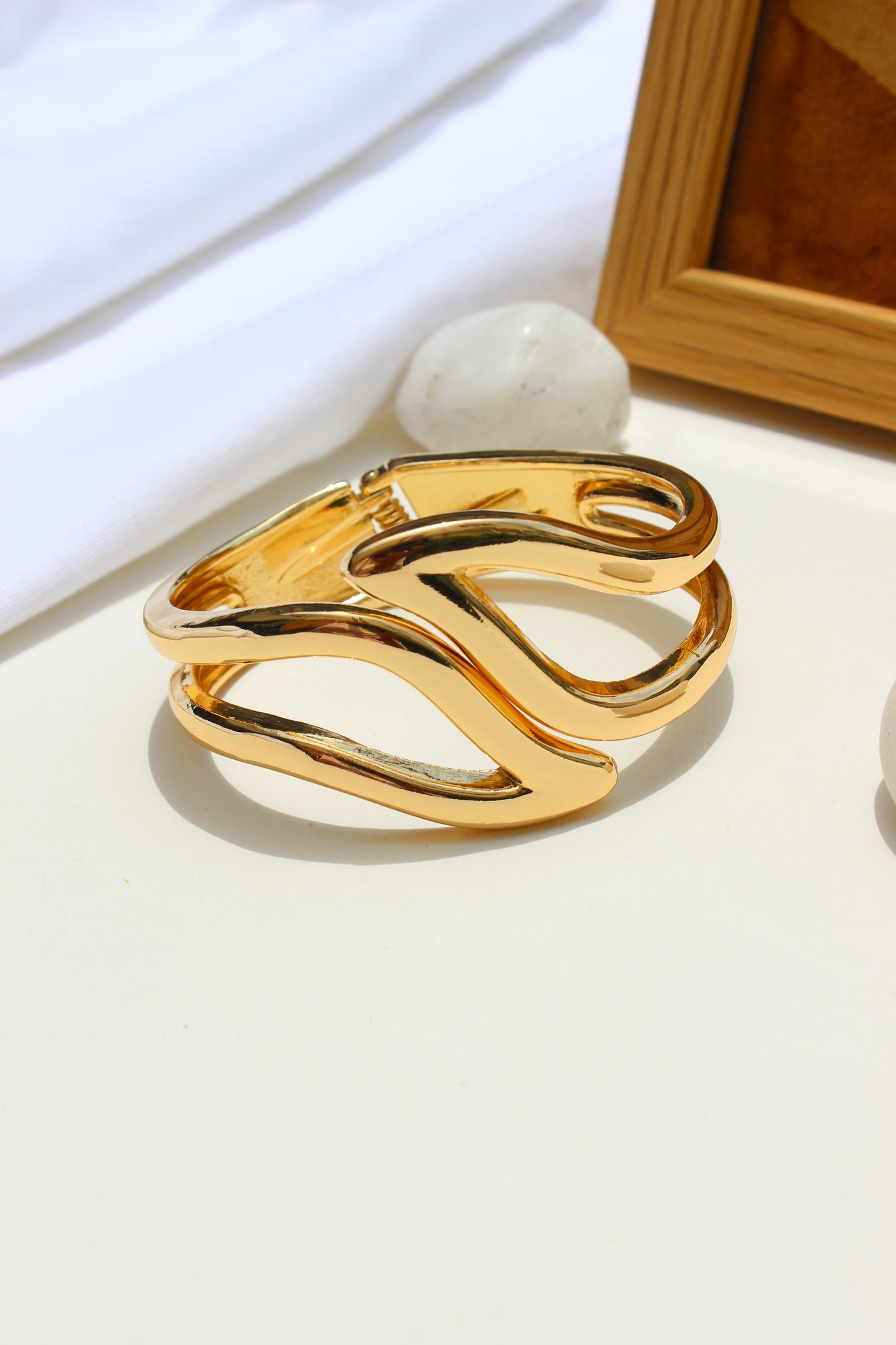 Heavy Petal Bracelet on a white surface with a wooden frame in the background