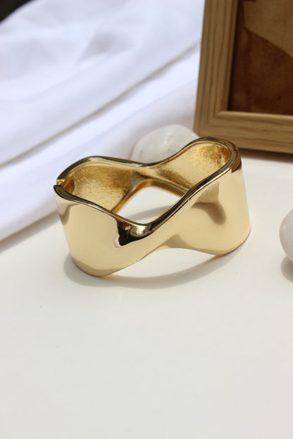 Molten Curve Bracelet on a white surface with a blurred background