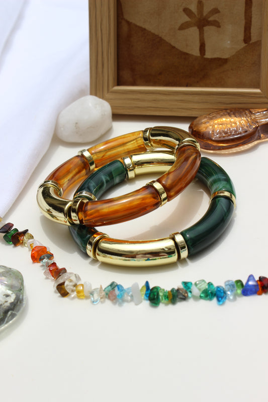 Amazonia Bangle Bracelets on a white surface with a wooden frame in the background