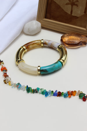 Colorhug Bangle Bracelets on a light surface nearby stones and wooden frame