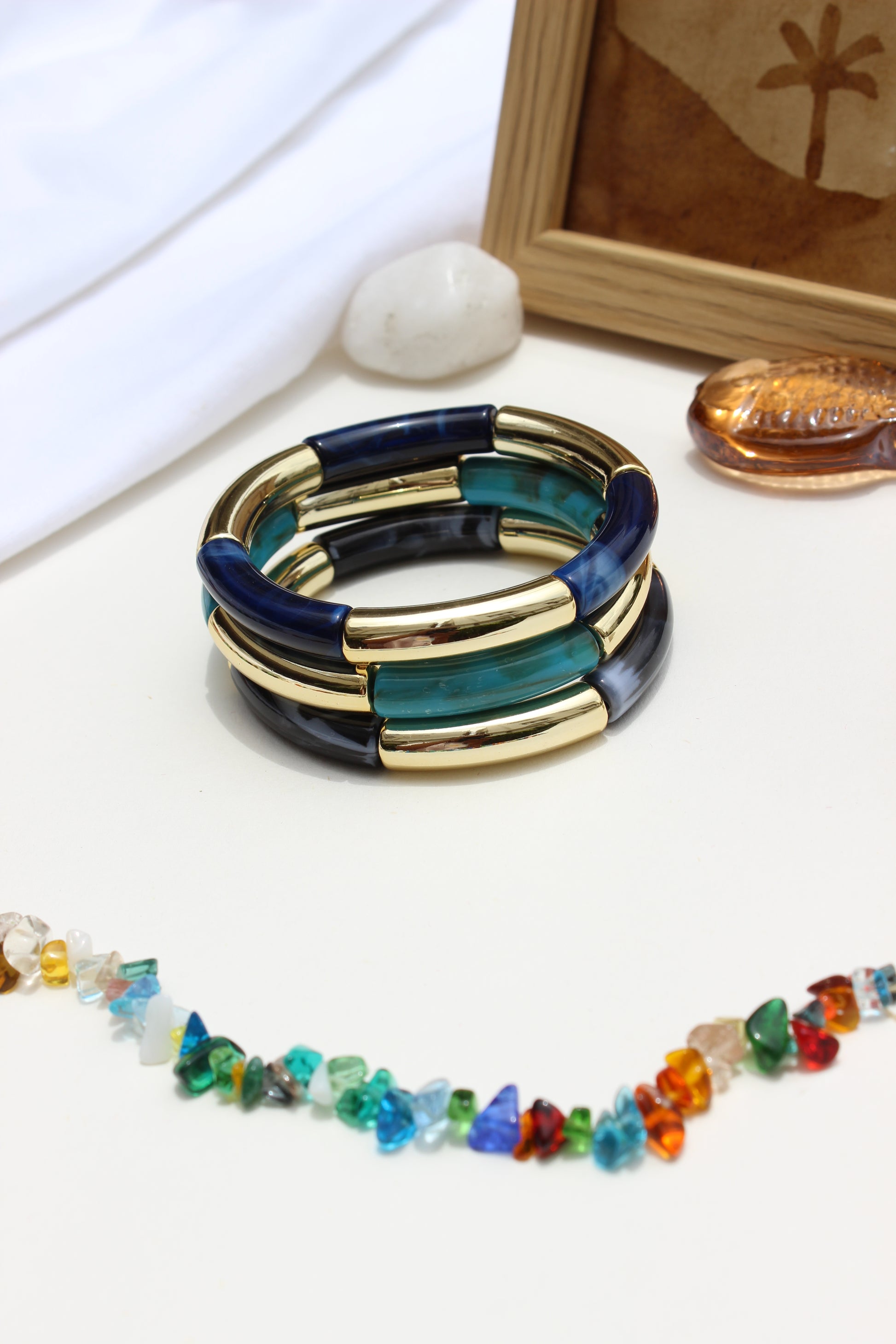 Mistplay Bangle Bracelets on a white surface with a wooden frame in the background