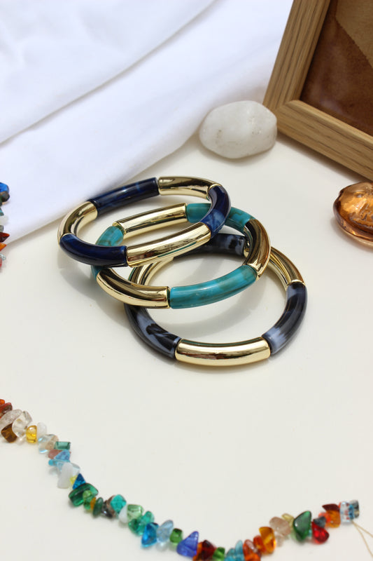 Mistplay Bangle Bracelets on a white surface with a wooden box and additional jewelry in the background