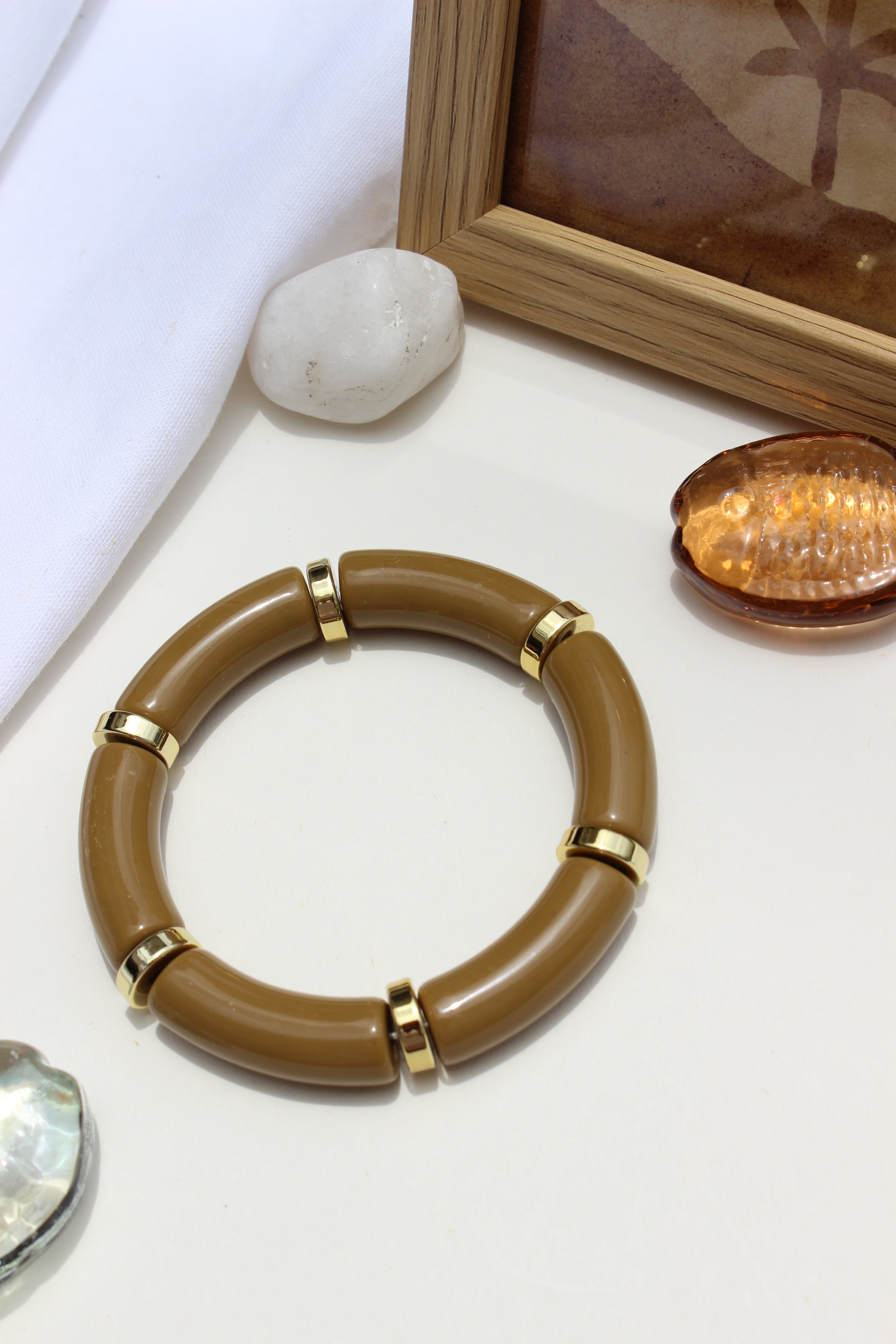 Mocha Toffee Bangle Bracelet on a white surface with decorative stones and wooden frame