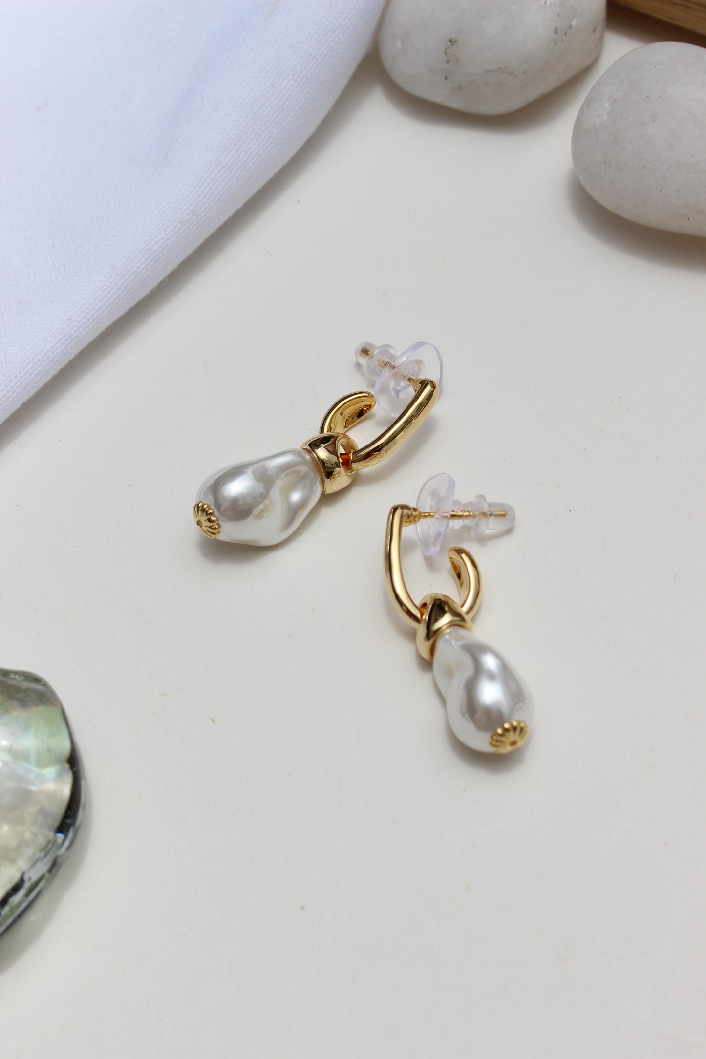 Ocean Muse Earrings on a light surface with stones in the background