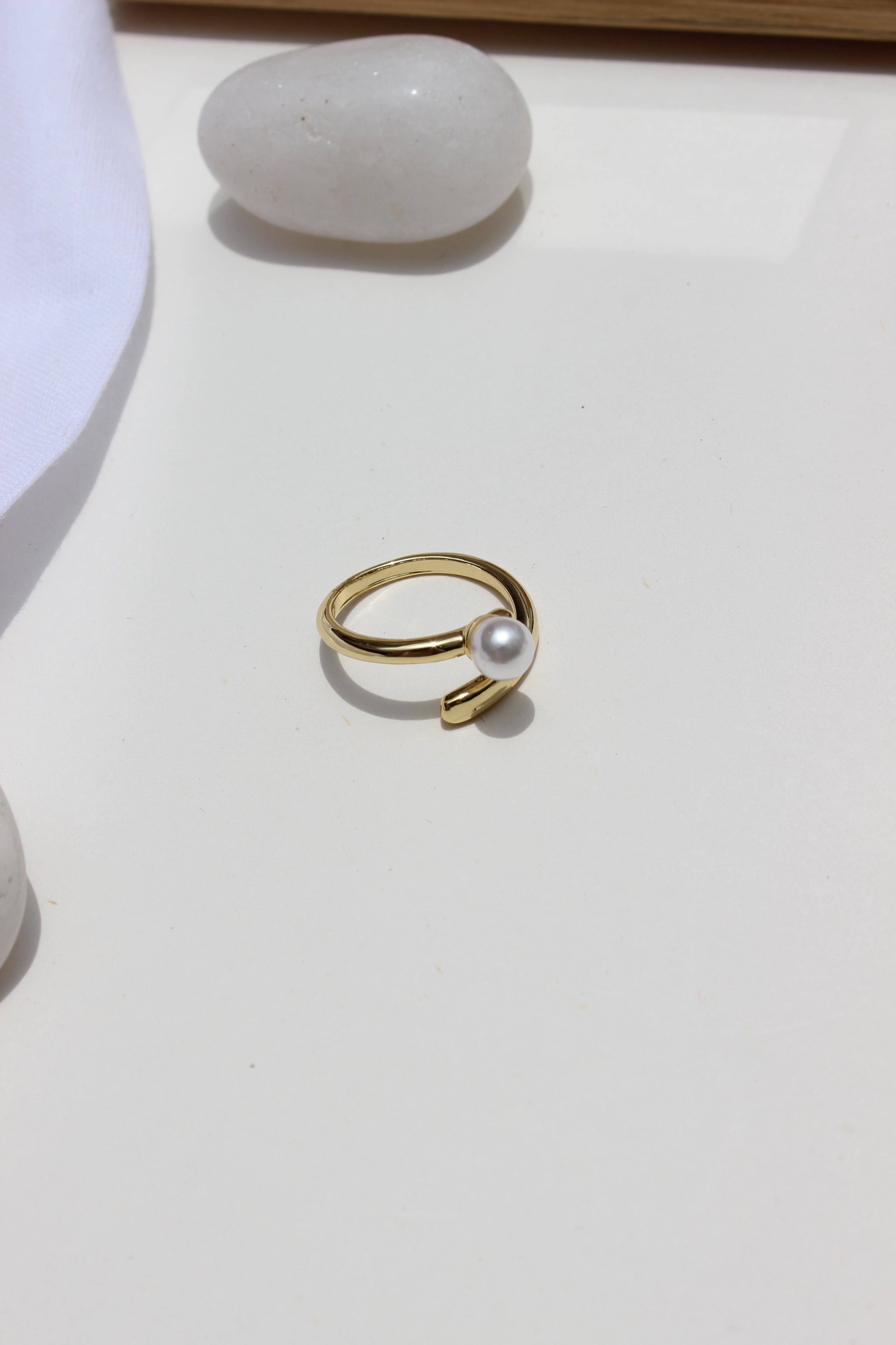 Folded Glow Ring with a pearl on a white surface