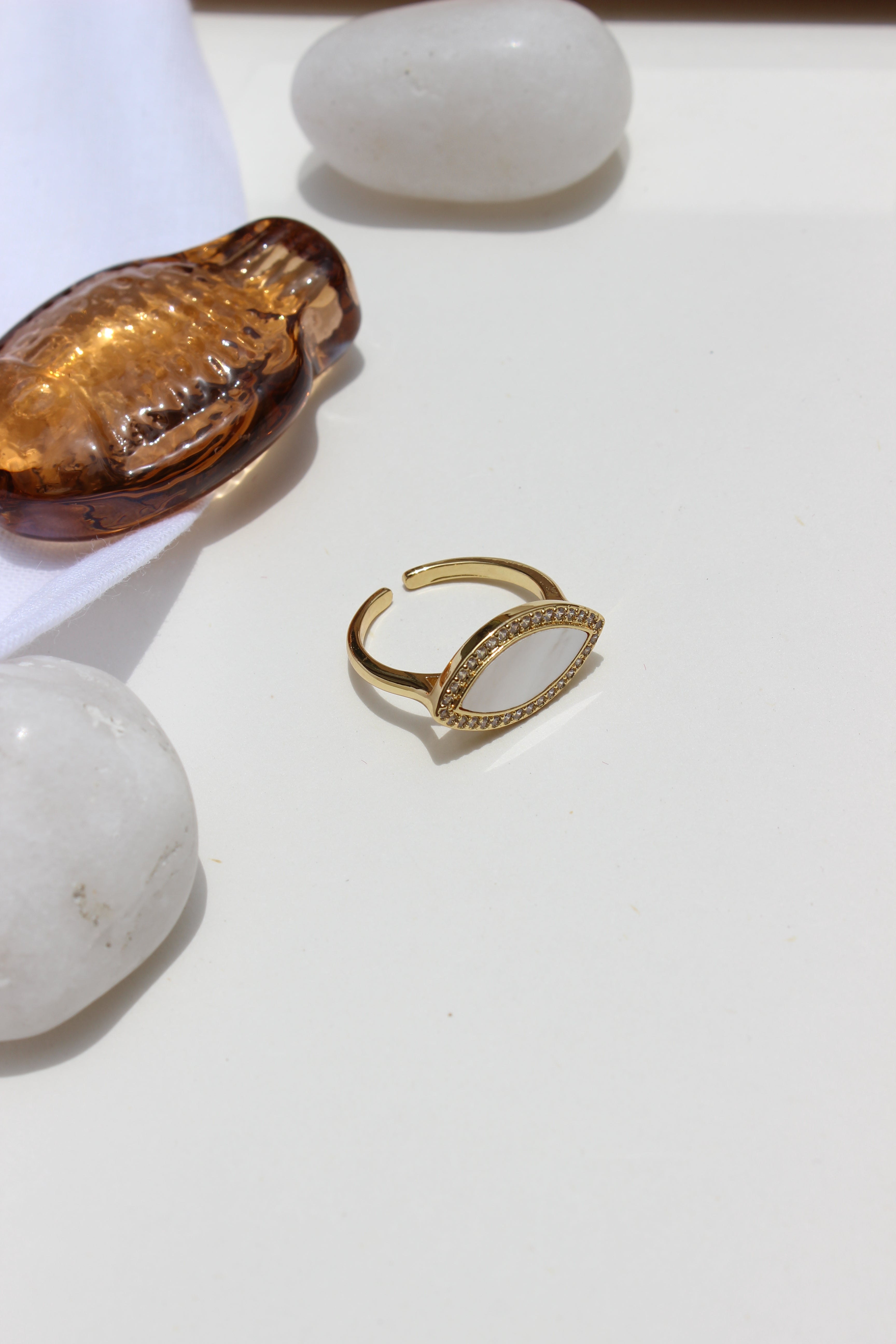 Moon Promise Ring on a white surface with a white stone and a brown seashell