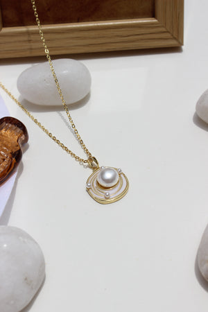 Bound in Pearl Pendant Necklace on a white surface nearby stones