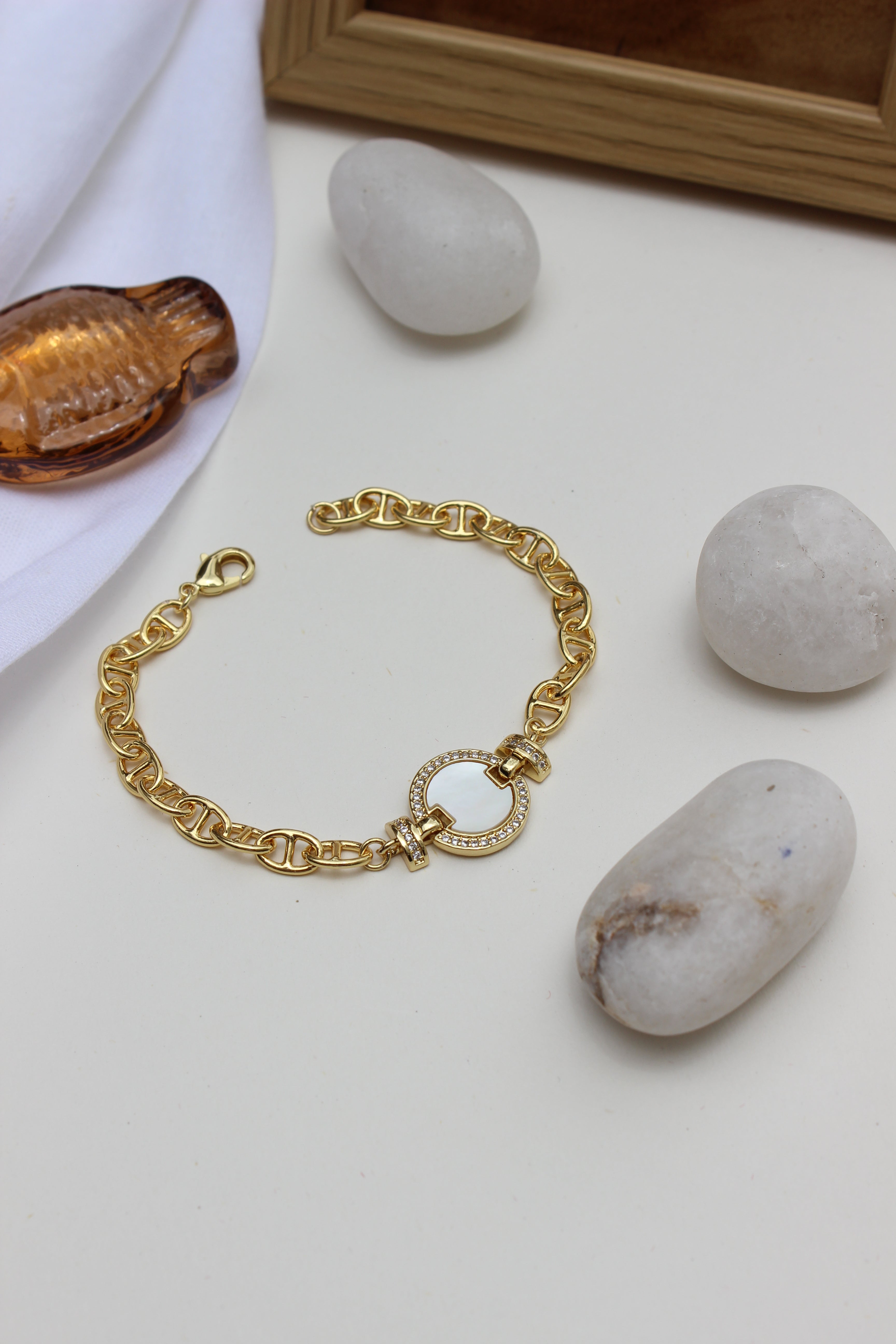 Sea of Light Bracelet on a light surface with stones and a wooden frame in the background