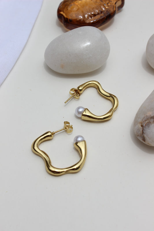 Pearl Fold Half Hoop Earrings on a light surface with stones