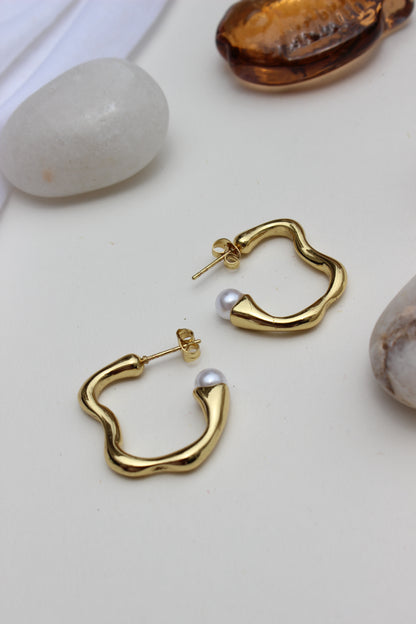 Pearl Fold Half Hoop Earrings on a white surface with seashells