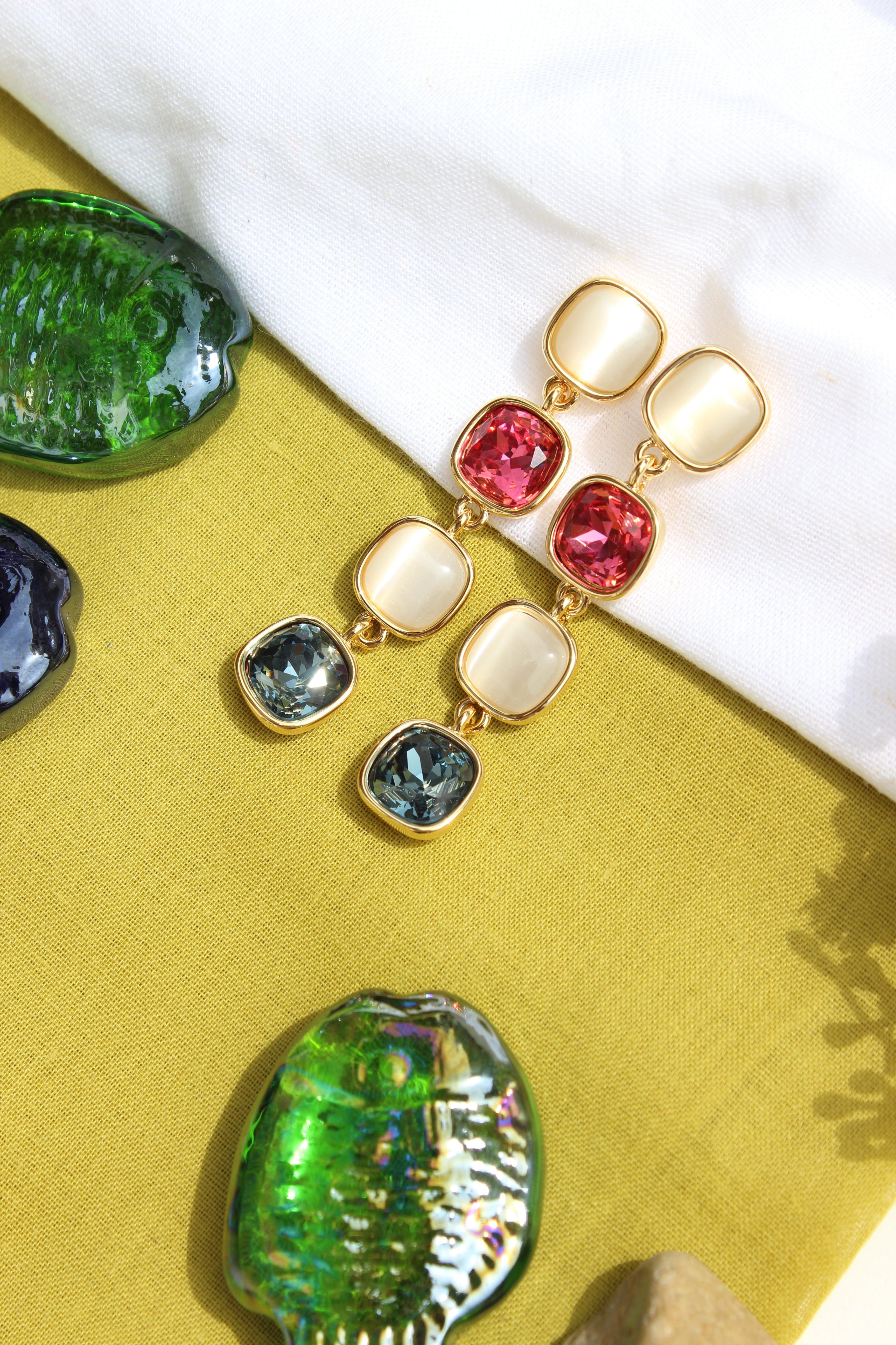 Colorful Skyfire Gleam Earrings with gemstones on a textured surface