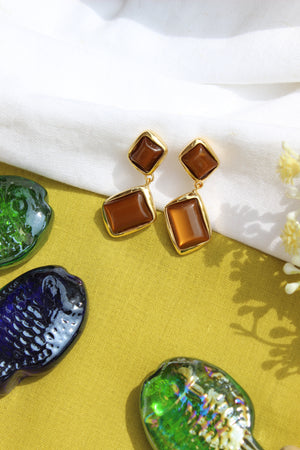 Amber Dust Earrings on a yellow surface with decorative shells