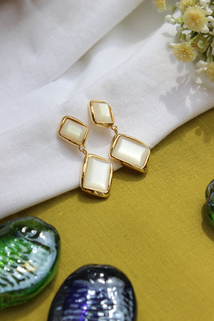 Ivory Drop Earrings on a white fabric background with decorative seashells