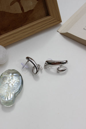 Midnight Curve Earrings on a white surface with a wooden frame in the background