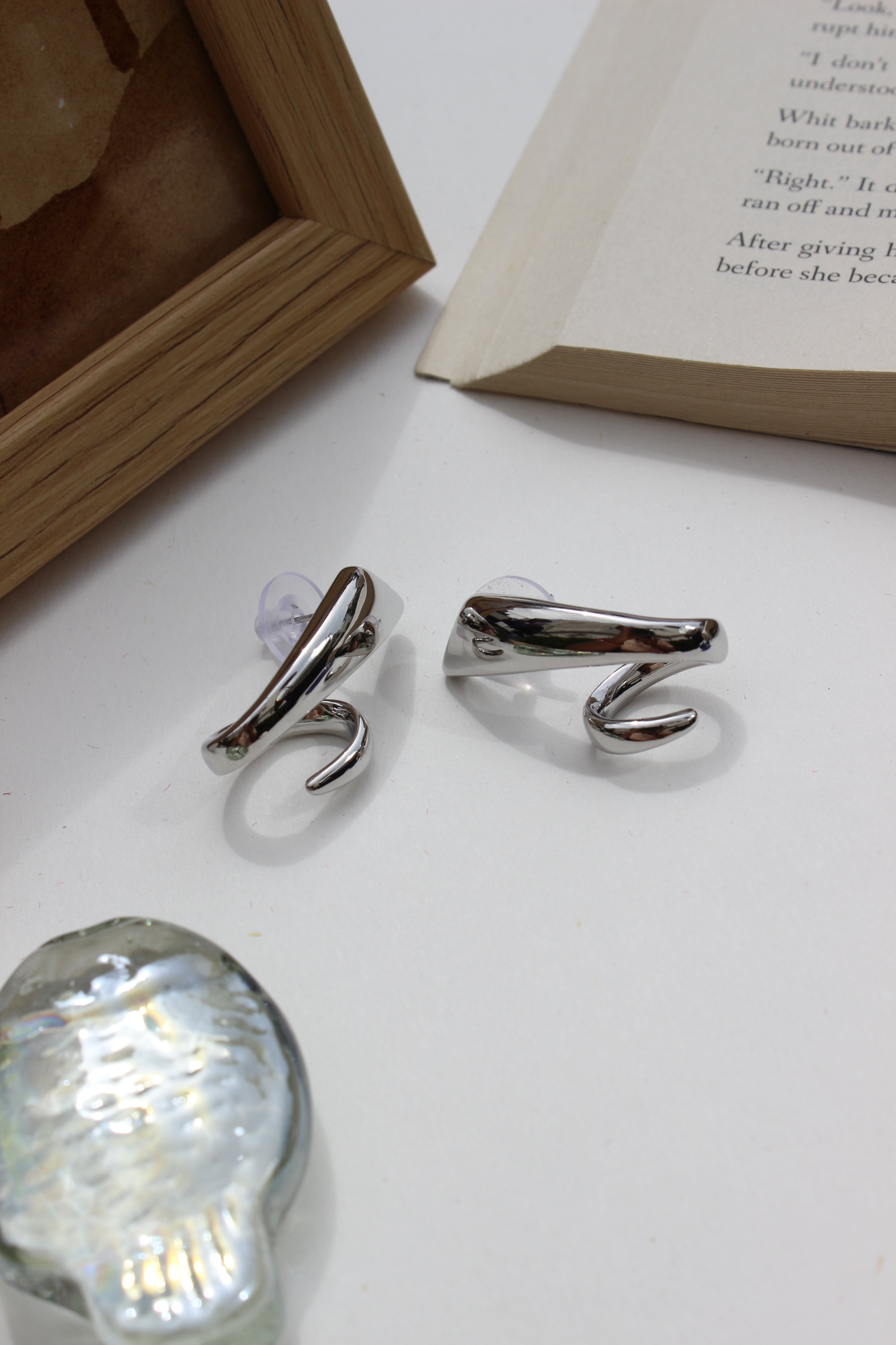 Midnight Curve Earrings on a white surface with a book and light fixture in the background