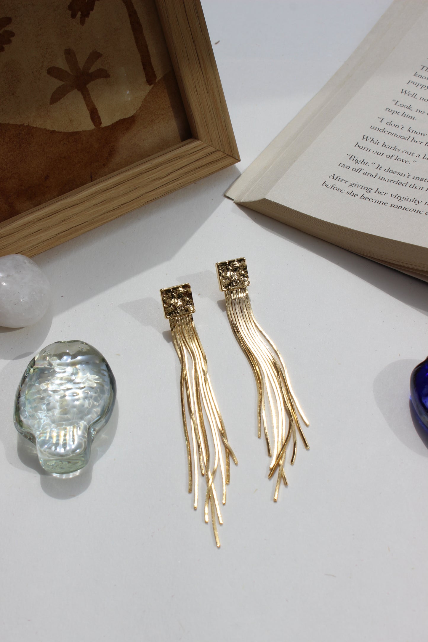 Soft Steel Earrings on a white surface with a book and crystal ball in the background