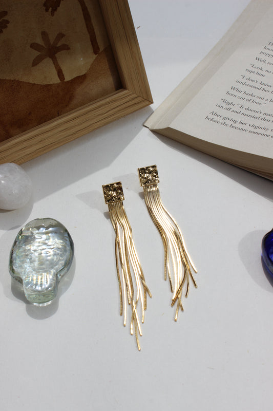 Soft Steel Earrings on a white surface with a book and crystal ball in the background